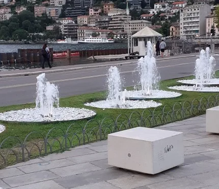 moderne fontane a zampillo circondate da ciottoli bianchi sul lungolago ,